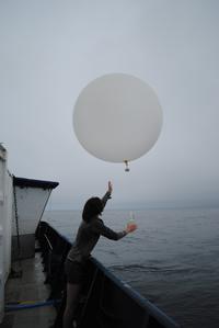 Recent graduate launching a balloon from a NOAH research vessel.