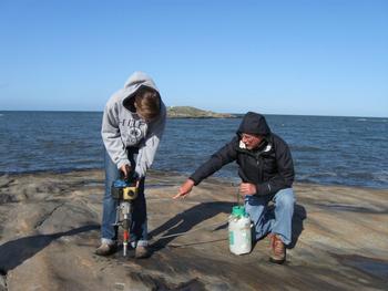 Student researcher collecting samples with a rock drill from a glacially polished outcrop, Halland Province, Sweden