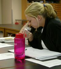 student examining and smelling a water sample during demo
